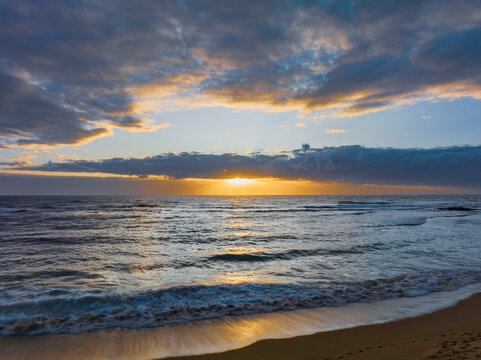 Sunrise over the ocean with clouds and sunburst