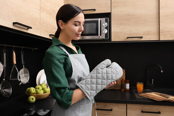 Woman wearing apron and oven glove in kitchen