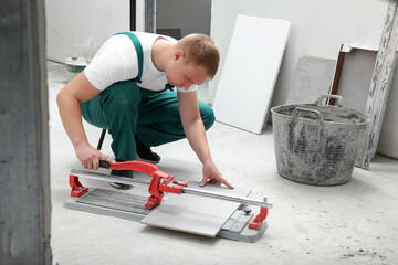 Worker using manual tile cutter in room