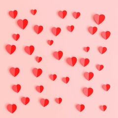 folded paper hearts scattered on pink background