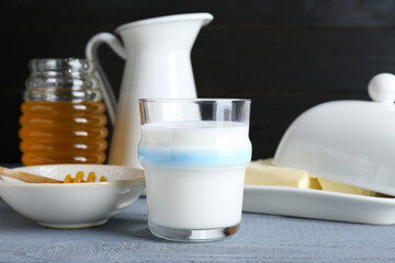 Glass with milk, honey and butter on grey wooden table