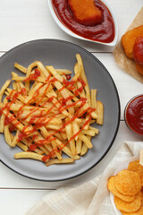 Tasty french fries, chicken nuggets and chips with ketchup served on white wooden table, flat lay