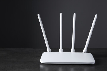 New stylish Wi-Fi router on black textured table. Space for text