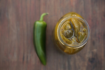 Fresh and pickled green jalapeno peppers on wooden table, flat lay. Space for text