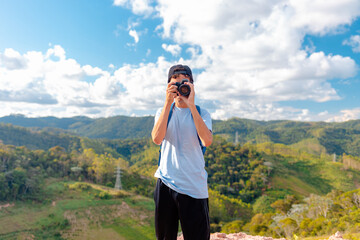 Traveler man on top of a mountain and taking pictures  with his professional camera of the landscape.