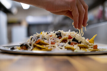 Cook sprinkling cheese on nachos in restaurant kitchen