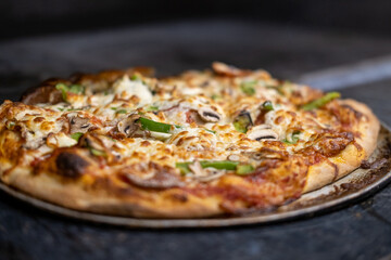 Closeup of alldressed pizza in wooden fire
