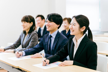 オフィス・会議室で笑顔で勉強するビジネスウーマン・会社員の男女（会議・セミナー・企業説明会・勉強会）