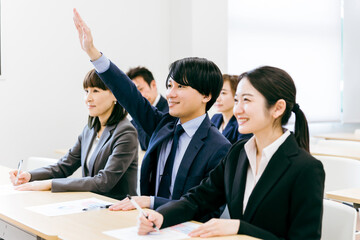 オフィス・会議室で挙手して積極的に質問・意見・発言するビジネスマン・会社員の男女（セミナー）