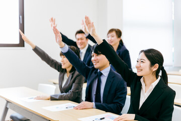 オフィス・会議室で挙手して積極的に質問・意見・発言するビジネスマン・会社員の男女（セミナー）
