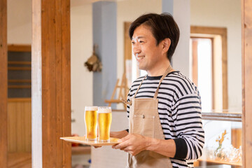 Fototapeta na wymiar グラスの生ビールを持つ居酒屋・飲食店・カフェスタッフ