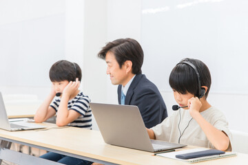 パソコンを使ってICT教育・プログラミング・英会話の勉強をする先生と子供（日本人）
