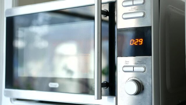 Using Microwave. Putting meal pot in and starting the timer