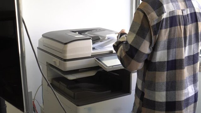 Document printing concept: Businessman arranging papers in front of laser printer control panel for copy scanner and document printing report chart chart in busy office
