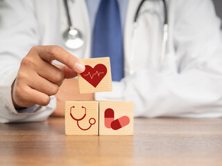 A doctor hand holding wooden cubes with icons of health