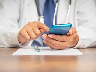 Doctor in a uniform using a smartphone while sitting at the desk