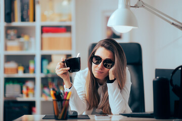 Hangover Woman Drinking Coffee Wearing Sunglasses in the Office. Sleepy businesswoman working after...