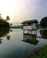 cool morning atmosphere in a village in Indonesia with huts above fish ponds