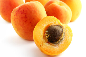 Ripe whole and halved apricots on white background