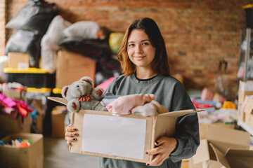 Volunteer teengirl preparing donation boxes for people. Donation clothing for refugees, support of war victims. Humanitarian aid concept.Helping people