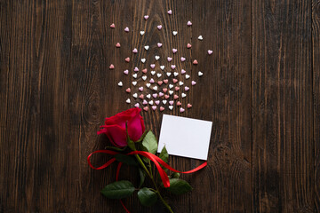 Red rose with postcard on wooden background. Happy Valentines Day postcard. Love concept for mothers day or valentines day. Valentine card with space for text