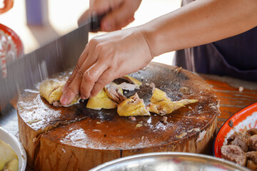 Asian woman's hand is cutting steamed chicken meat.Cooking ideas