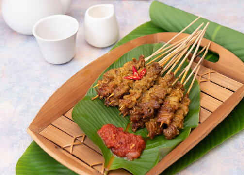 Sate usus or chickens intestines satay. traditional Indonesian street food. On banana leaf and traditional bamboo plate. Selective Focus
