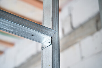 Frame for drywall from a metal profile for a wall close-up on a blurred background. Connection of parts during construction