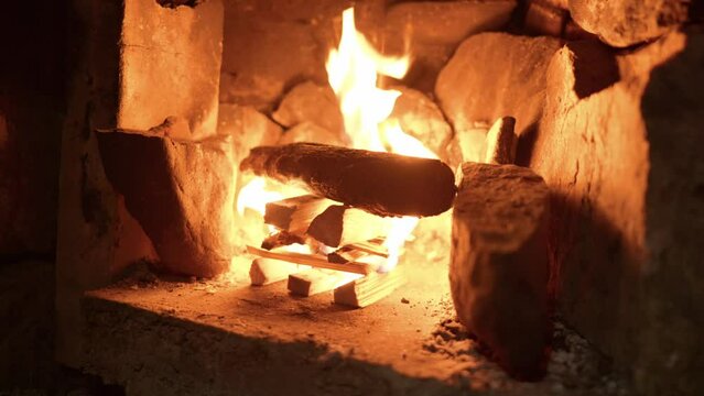 A freshly lit log fire gives out an orange glow and wooden kindling burns.