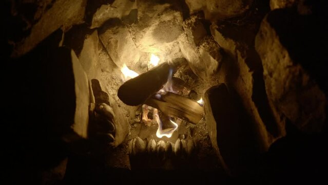 A top down view of wild foraged mussels slowly cook in front of an open log campfire in an old fireplace.