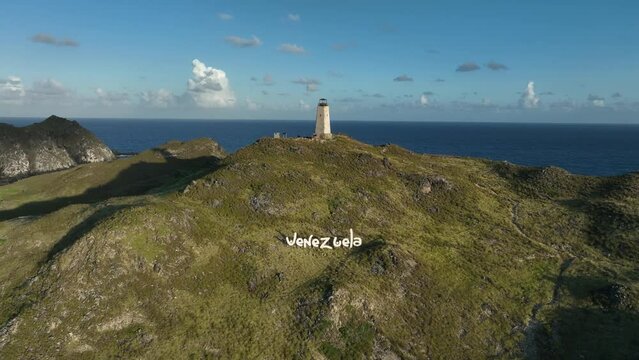 Early morning aerial view approaching the lighthouse and sign Venezuela on the hillside. Gran Roque Island in Los Roques Archipelago, Venezuela.