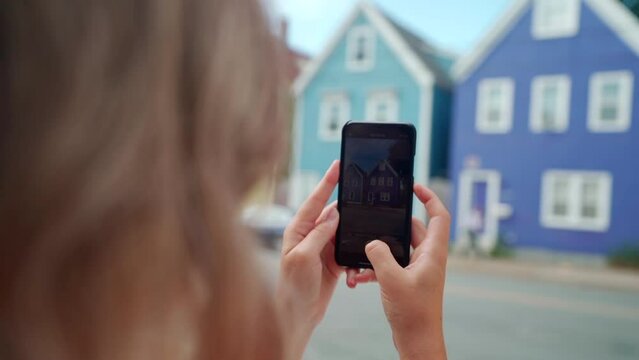 Woman taking photo of colourful buildings on her cell phone in Halifax, Nova Scotia, Canada