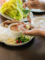 Enjoy eat with Vietnamese Meatball Wraps (Nam-Neung), Pork Sausage wraps with fresh vegetables in rice paper, generous platter eat with sweet sauce. Vietnamese Pork Sausage and salad. Selective focus.