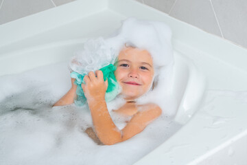 Kids bathing. Kid in a bath tub. Washing in bath with soap suds on hair. Child taking bath. Closeup portrait of smiling kid, health care and kids hygiene. Kids face in bath tub with foam.