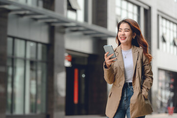 Lifestyle of beautiful Asian women going to work happily walking and talking on the phone close to her office building