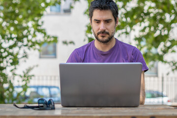 man with a beard seen from the front with his pc on a table in the park