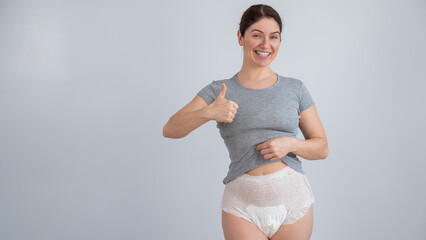 Woman in adult diapers smiling and showing thumbs up. Urinary incontinence problem. 