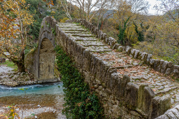 Old stone bridge in Klidonia  during fall season.  This arch bridge was built in 1853 and it is...