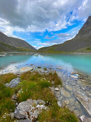 Transparent turquoise water mountain lake Karakabak among stone rocks with a day in Altai in summer under a blue sky.