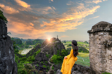 Asian woman on Hang Mua viewpoint at Tam Coc, Ninh Binh. Vietnam and sunset sky