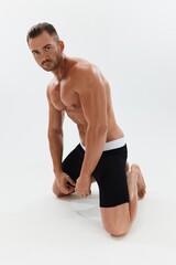 Obraz premium Man athletic body bodybuilder in briefs with naked torso abs full-length in the background, fitness classes. Advertising, sports, active lifestyle, competition, challenge concept.