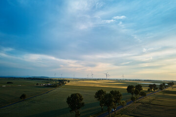 Aerial view of windmill turbine generator against beautiful sunset sky in countryside area, Concept of clean, renewable, sustainable, alternative energy