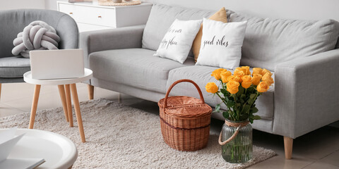 Interior of stylish living room with yellow roses in vase and wicker basket
