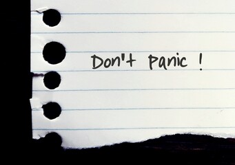 Torn ripped lined note paper with hand written text DONT PANIC! - concept of self motivation to...