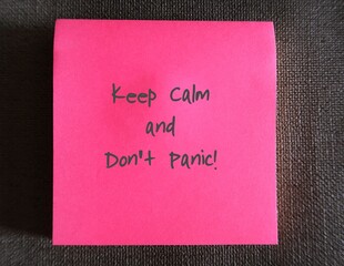 Pink note on dark background with text written KEEP CALM AND DONT PANIC , self reminder to warn...