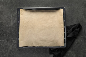 Baking tray with parchment paper and napkin on dark background