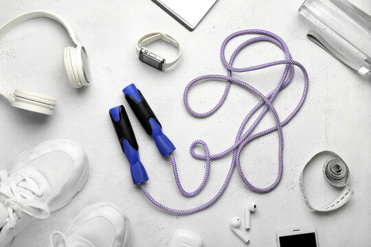 Skipping rope, gadgets, measuring tape and sneakers on white background