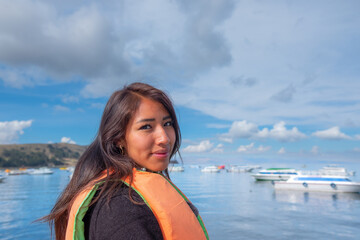 Fototapeta premium smiling young latin woman sightseeing in a boat on the shores of lake titicaca in bolivia