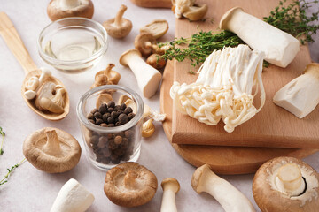 Fresh mushrooms, allspice, oil and thyme on light background
