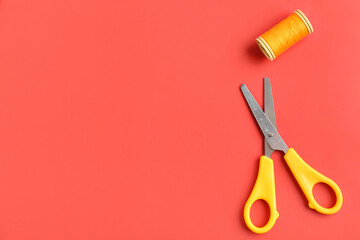 Scissors and thread spool on color background